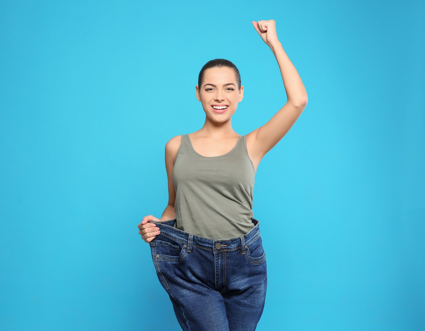 Slim Woman in Oversized Jeans on Color Background. Weight Loss